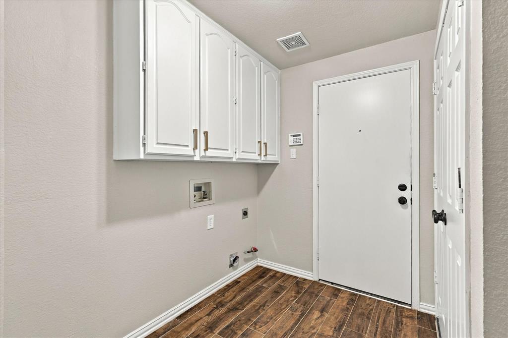 FUNCTIONALITY WITH A TOUCH OF STYLE! Beautiful white overhead cabinetry, rich wood-look tile flooring, and a dedicated laundry space make everyday organization effortless.