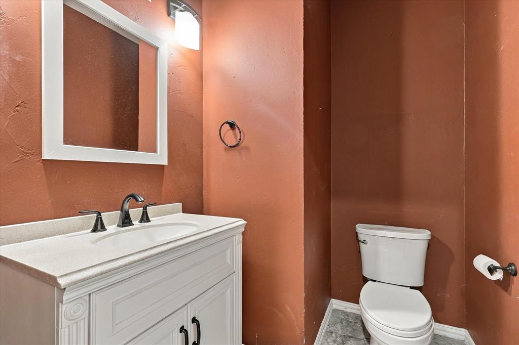 A TOUCH OF BOLD SOPHISTICATION! Warm, dramatic wall tones, a beautifully detailed vanity, contrasting white countertop, and stylish dark fixtures bring distinctive personality to this conveniently located powder room.