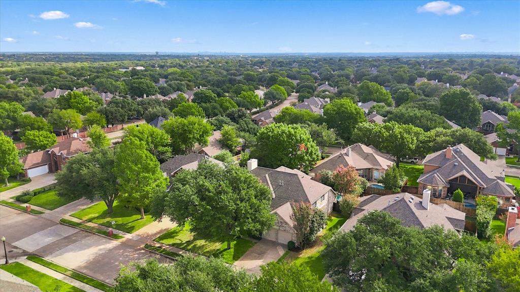 AN EXCEPTIONAL FLOWER MOUND SETTING! Sweeping aerial views showcase an established neighborhood filled with beautiful homes, mature trees, and lush greenery, creating an inviting residential landscape.