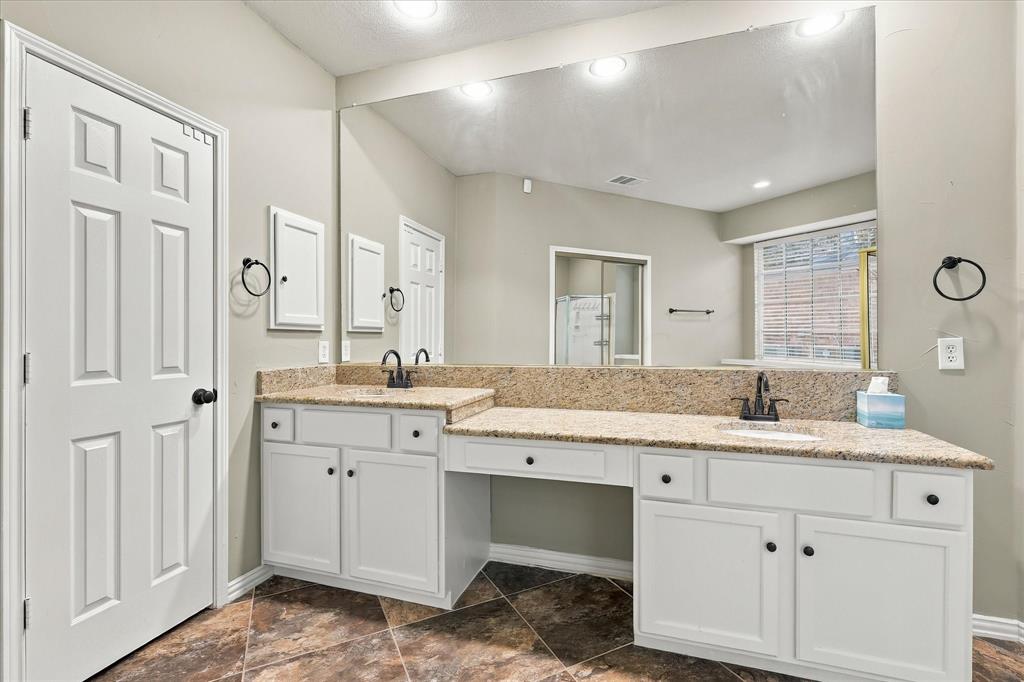 EVERYDAY LUXURY, BEAUTIFULLY DESIGNED! An expansive dual-sink vanity features gorgeous granite countertops, a generous wall-to-wall mirror, abundant cabinet storage, and a dedicated seated vanity area.