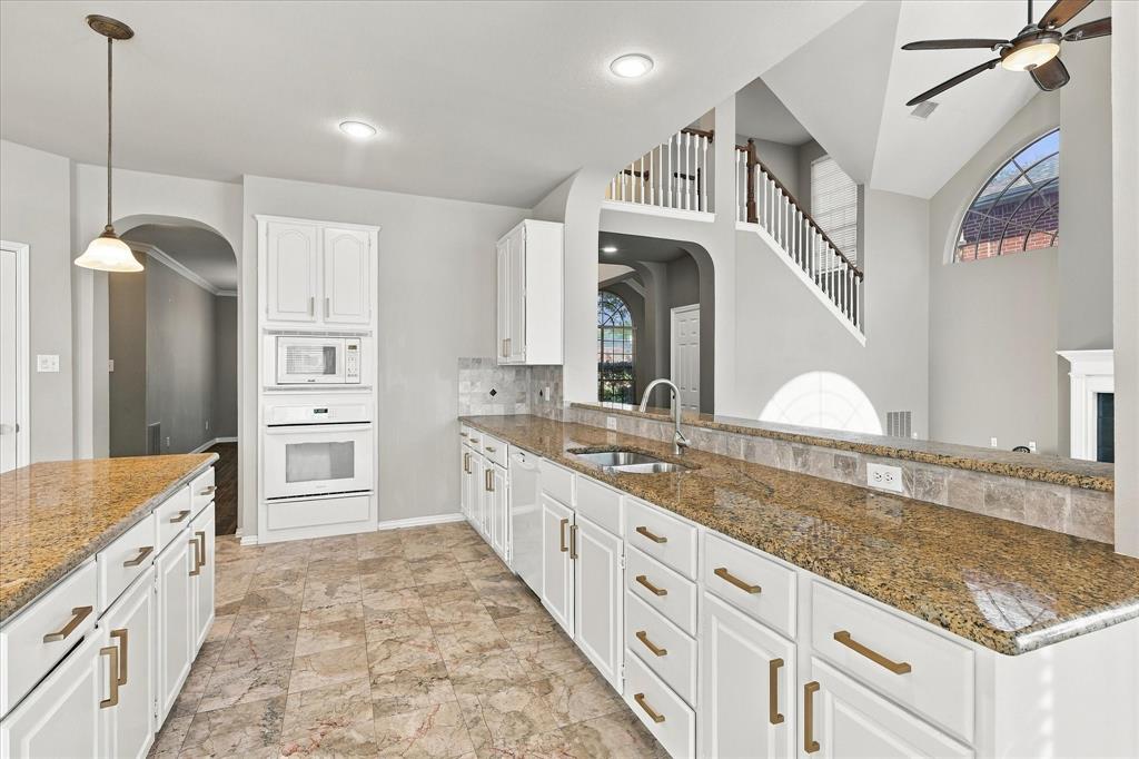 EFFORTLESS ENTERTAINING STARTS HERE! A spacious kitchen with granite countertops, generous cabinetry, and a convenient breakfast bar opens to the home's stunning two-story living area, creating an inviting atmosphere for memorable gatherings.