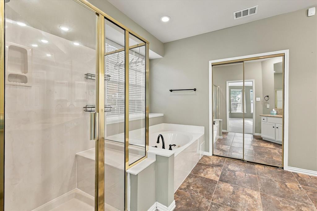YOUR PERSONAL SPA EXPERIENCE! Unwind in the luxurious soaking tub or refresh in the separate glass-enclosed shower. Beautiful tile flooring, abundant natural light, and classic finishes create an inviting space for relaxation.