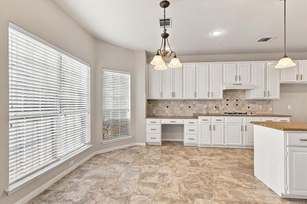 A BRIGHT AND INVITING HEART OF THE HOME! Beautiful white cabinetry with a built in desk, generous countertops, decorative tile backsplash, and a sun-filled breakfast area create a welcoming kitchen with wonderful space for cooking, gathering, and everyday enjoyment.