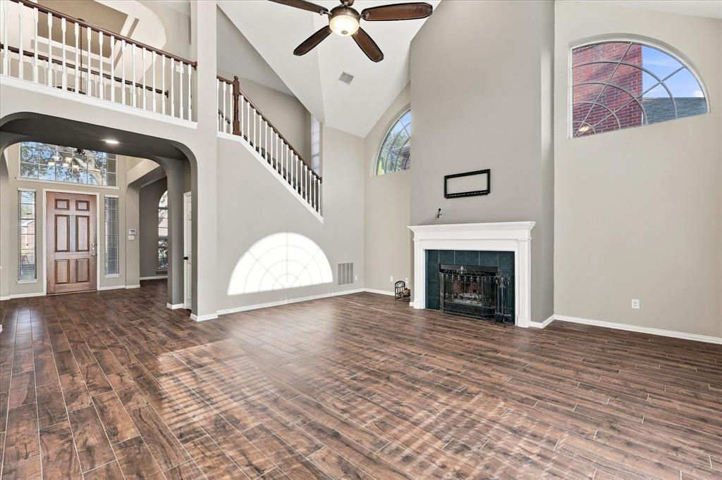 AN ABSOLUTE ARCHITECTURAL SHOWSTOPPER! Soaring ceilings, dramatic arched windows, an elegant fireplace, and a sweeping second-story overlook make this spectacular living room the centerpiece of the home. Rich flooring and abundant natural light create a truly unforgettable atmosphere.