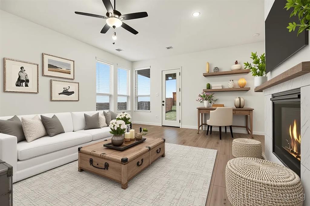 Fireplace with stone-style surround and wood mantel, wood-finish flooring, recessed lighting, ceiling fan, and floating wall shelves Fireplace with stone-style surround and wood mantel, wood-finish flooring, recessed lighting, ceiling fan, and floating wall shelves