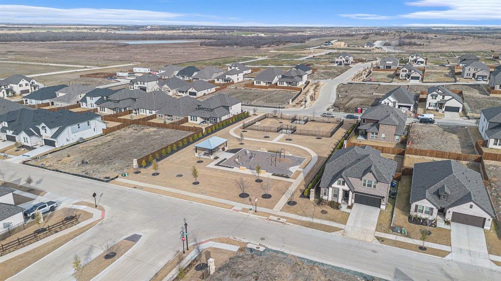 Aerial view of neighborhood amenities featuring a covered pavilion, multi-use play structure, perimeter fencing, and concrete pathways