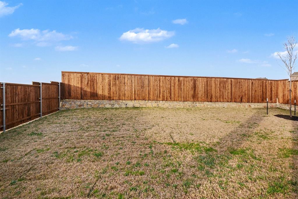 Private backyard featuring a tall wood privacy fence and a stone retaining wall