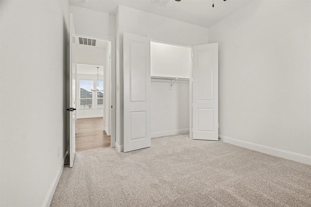 Neutral-toned wall-to-wall carpeting, two-panel interior doors, built-in closet with wire shelving, and overhead ceiling fan