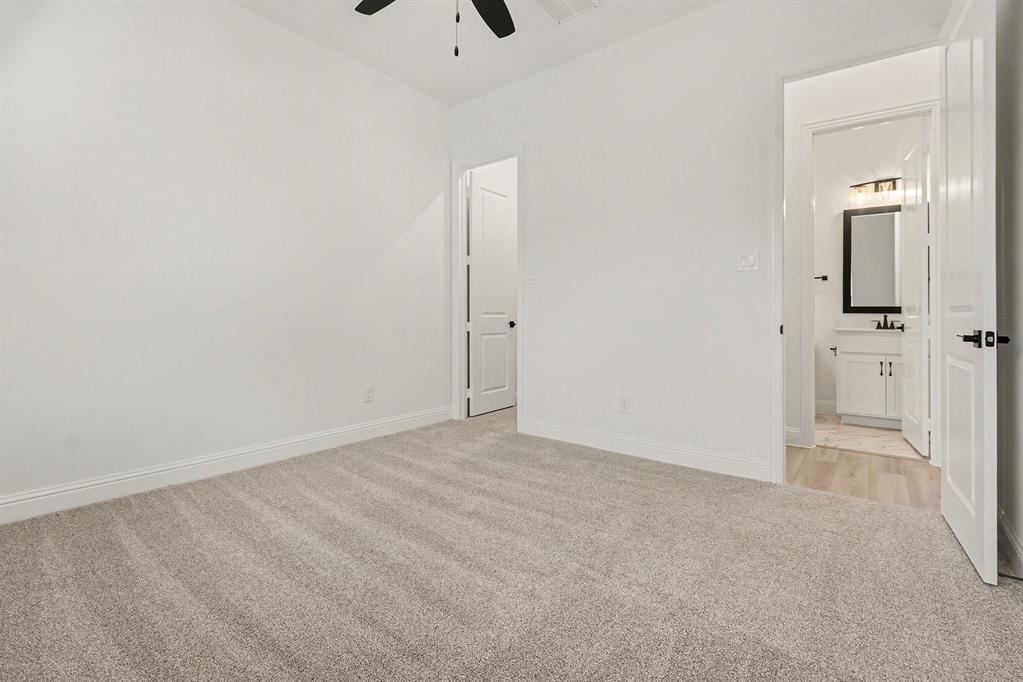 Interior room featuring neutral wall-to-wall carpeting, white walls, and a ceiling fan