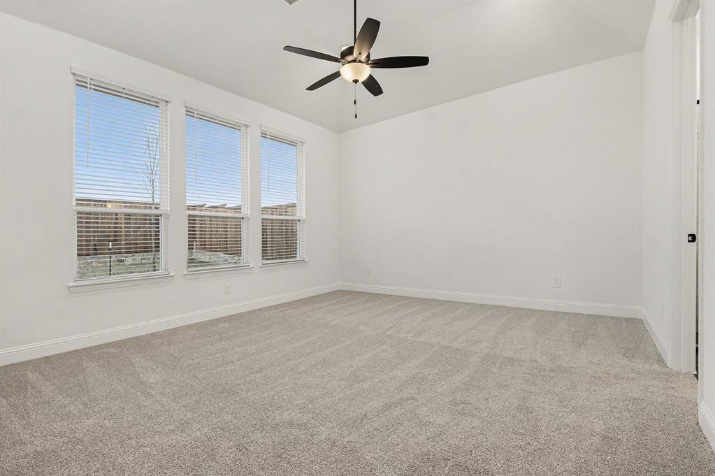 Vaulted ceilings featuring a central overhead fan with light fixture, neutral wall-to-wall carpeting, and triple-pane window configuration