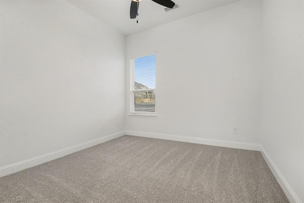 Neutral interior space featuring high ceilings, wall-to-wall carpeting, a single-hung window with blinds, and an integrated ceiling fan