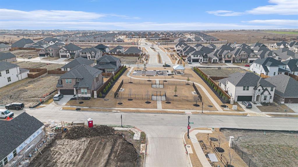 Aerial perspective of a neighborhood featuring a fenced common area, paved walking paths, a covered pavilion, and uniform residential street layouts