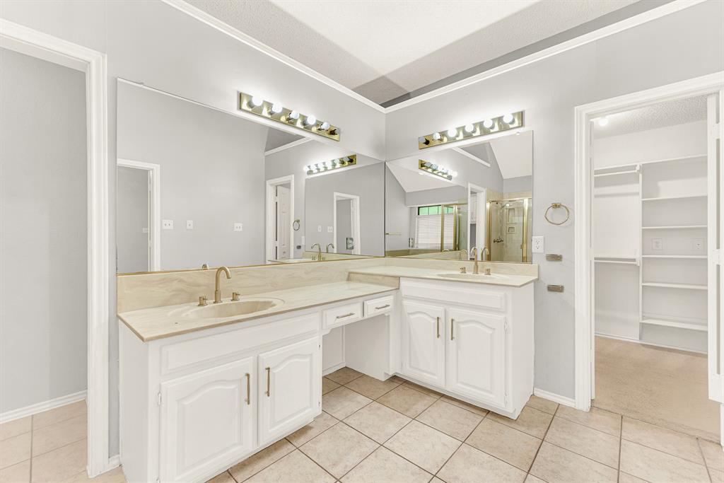 An L-shaped double vanity offers generous counter space while connecting directly to a spacious walk-in closet. Imagine easily selecting your daily outfit from the organized storage just steps away.