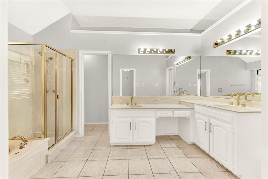 Warm brass accents frame the glass shower enclosure, adding classic detail alongside expansive vanity mirrors. Visualize your unhurried morning routine, enjoying glowing theatrical lighting as you get ready