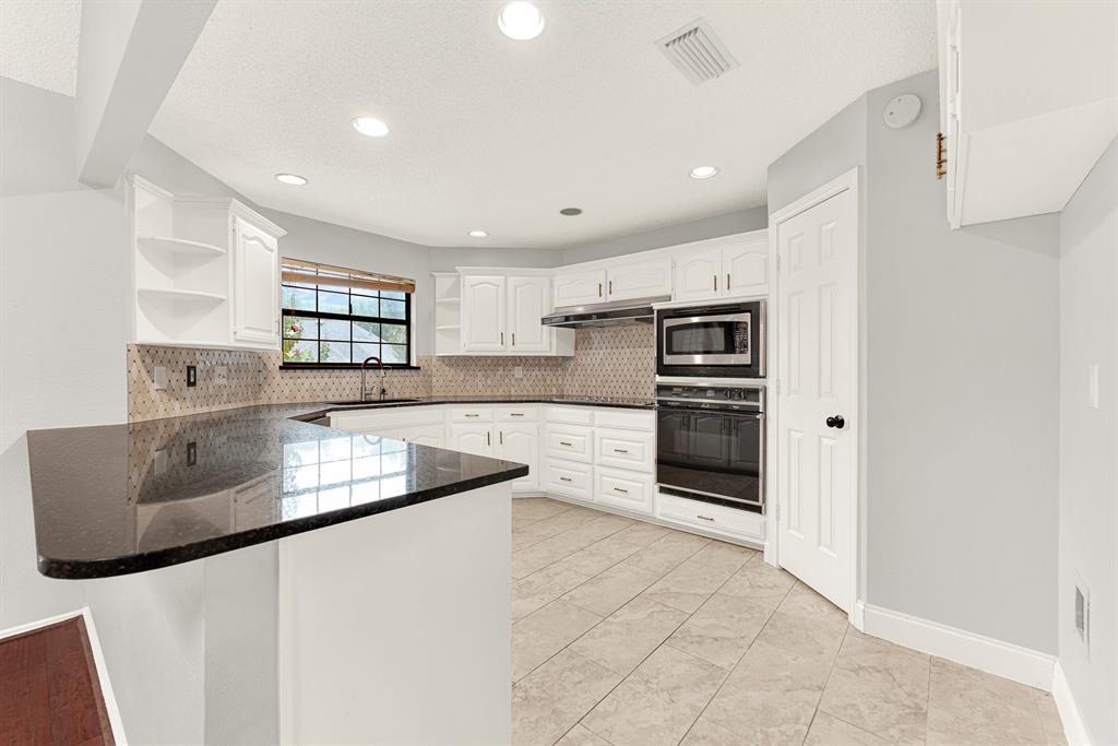 Deep polished granite countertops sweep around bright cabinetry, reflecting crisp recessed ceiling lighting throughout the culinary space. You will love pouring morning juice here while checking emails in this open, functional kitchen