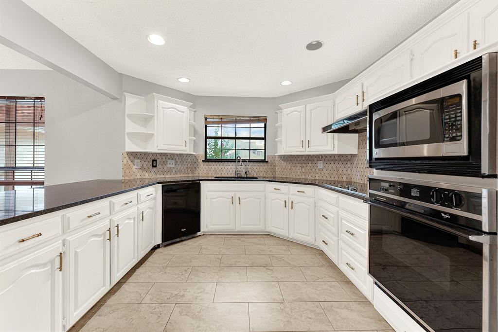 A patterned tile backsplash wraps seamlessly behind crisp white cabinetry, balancing texture with a clean, airy feel. Picture baking holiday treats while warm aromas fill every corner of this inviting layout.