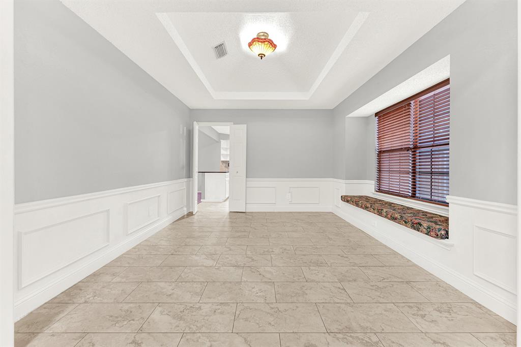 An elegant recessed tray ceiling draws the eye upward, catching soft glow from the central light fixture. Picture hosting intimate dinner parties where warm conversations linger long after dessert is served