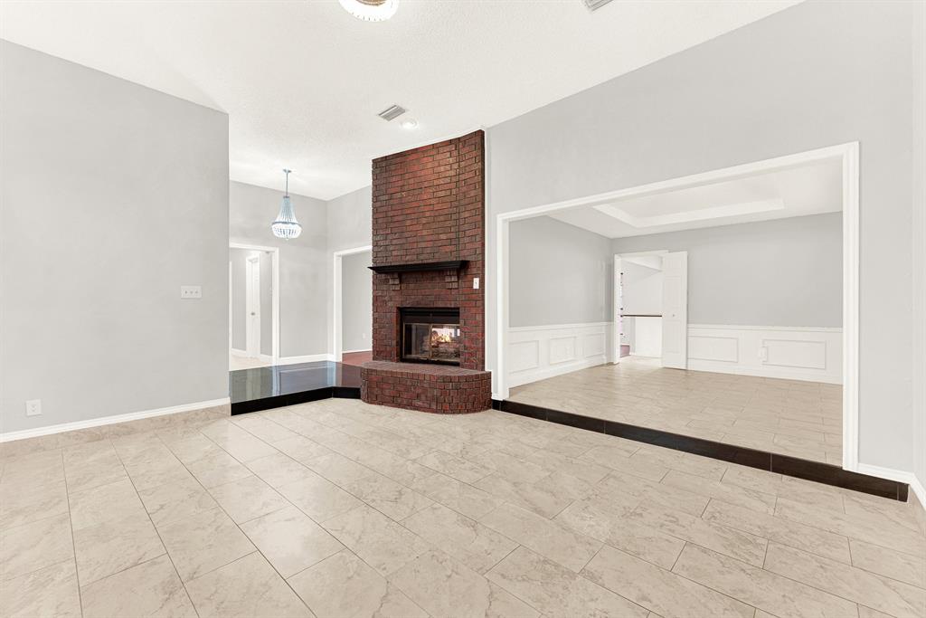 A floor-to-ceiling brick fireplace serves as a grounding centerpiece, anchoring the open layout. Imagine hosting cozy game nights with friends curled up around a crackling hearth.