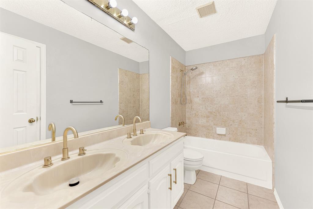 Warm neutral tilework wraps around a built-in tub and shower, complemented by a wide double-sink vanity. You can easily envision your guests enjoying a refreshing, hotel-like morning routine in complete comfort.