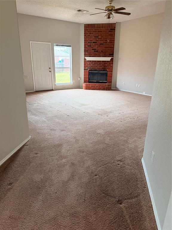 Vaulted ceiling with a ceiling fan, brick fireplace, and a large window Vaulted ceiling with a ceiling fan, brick fireplace, and a large window
