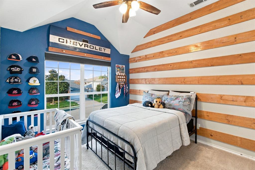 Vaulted ceiling with an integrated wooden ceiling fan, horizontal natural wood wall paneling, and a large divided-light window