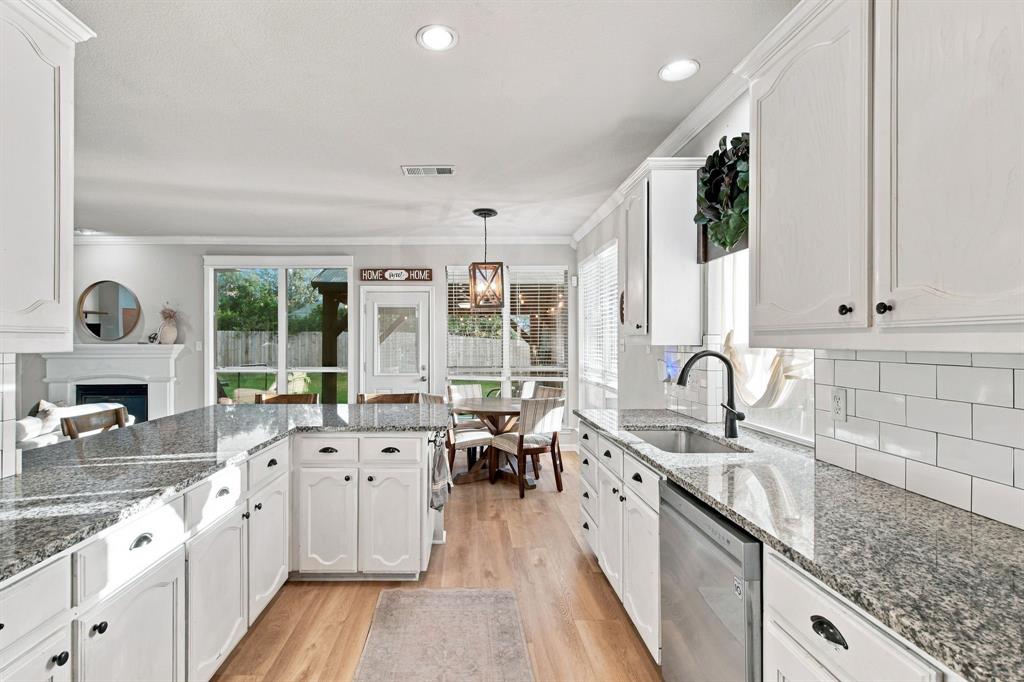 Kitchen featuring white shaker-style cabinetry, speckled stone countertops, a subway tile backsplash, stainless steel dishwasher, and wood-finish flooring