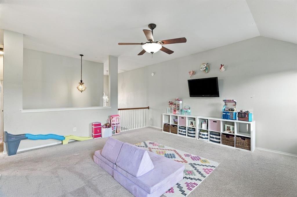 Vaulted ceiling featuring a central lighted ceiling fan, decorative hanging pendant light, and a white baluster railing overlooking the lower level