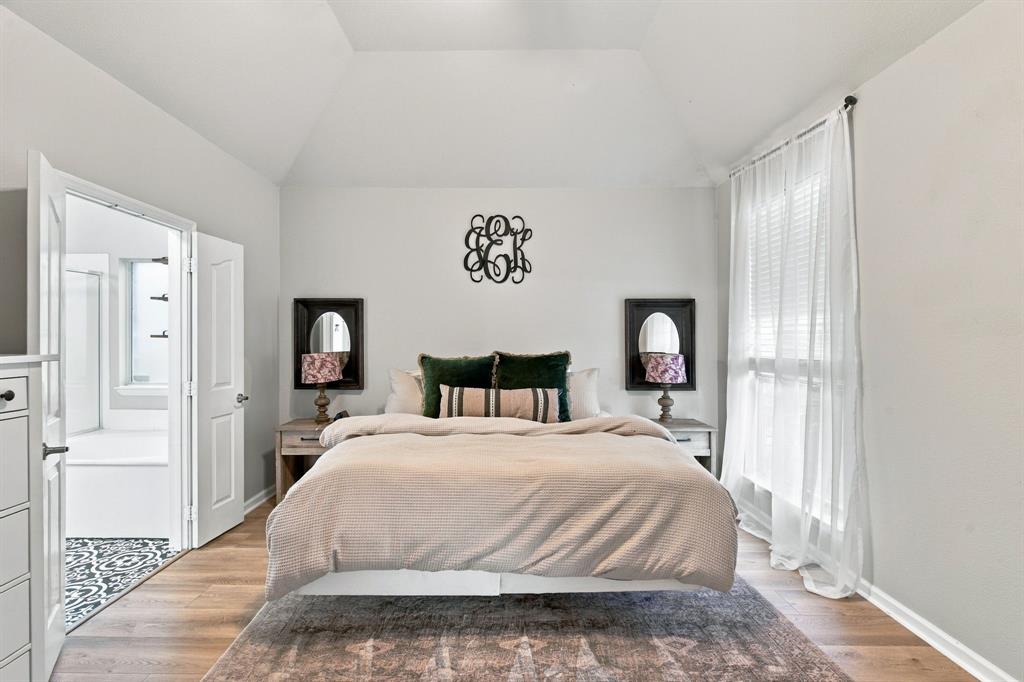 Bedroom featuring a vaulted ceiling, wood-finish flooring, and a large window