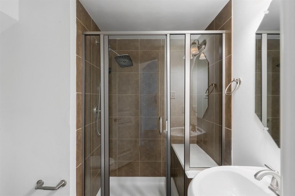 Glass-enclosed shower with brown tile surround and a built-in bench