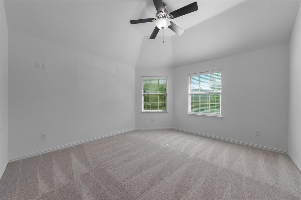 Vaulted ceiling with a ceiling fan, two windows, wall-to-wall carpeting, and white wall finishes