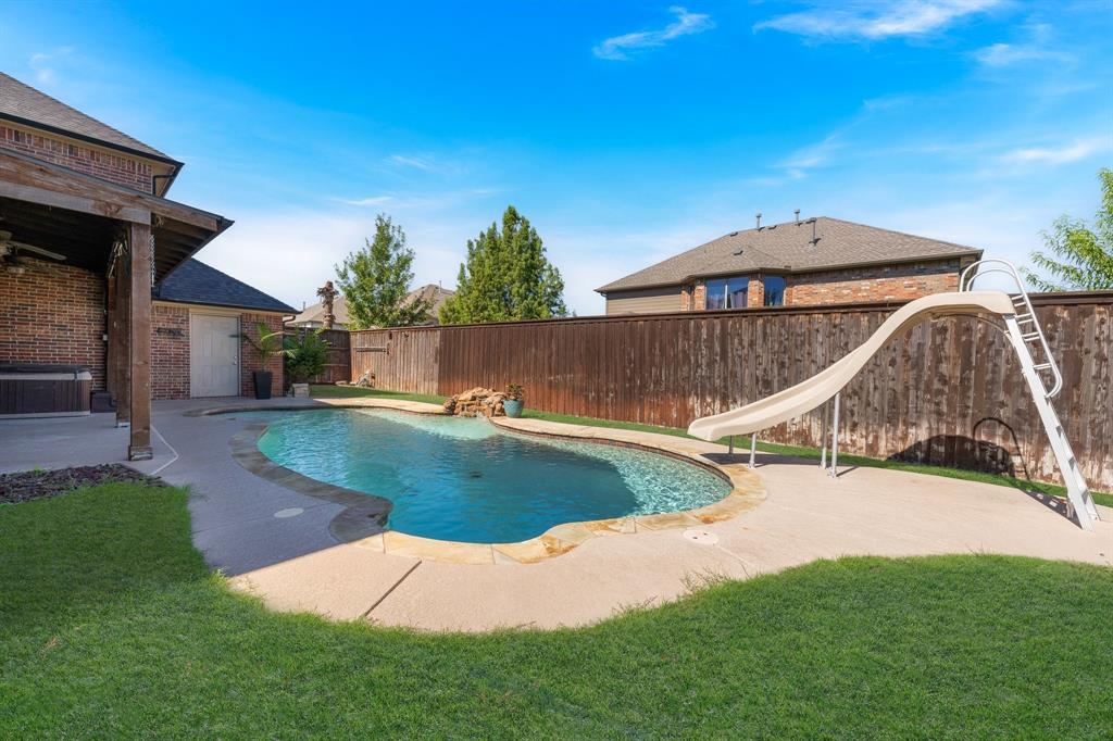 In-ground swimming pool with a slide, stone coping, and a water feature