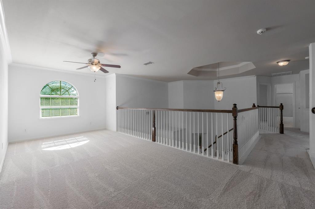 Arched window with blinds, ceiling fan, carpeted flooring, decorative chandelier, and tray ceiling detail
