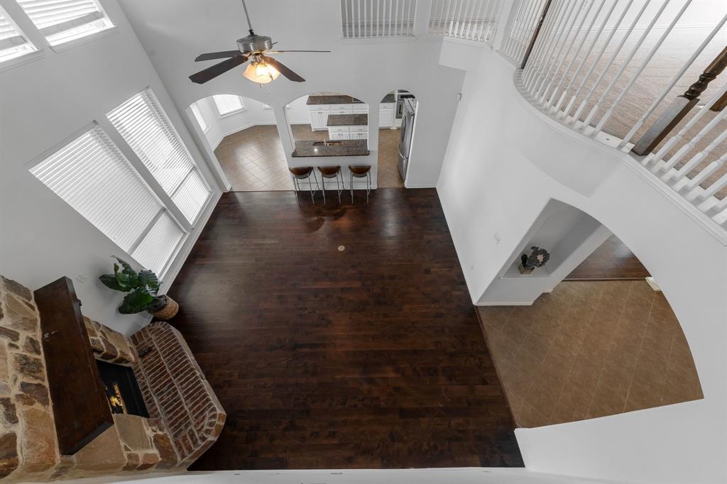 Two-story living area featuring wood-finish flooring, a stone and brick fireplace, and arched entryways
