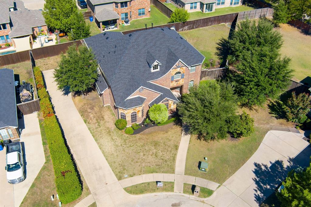 Brick exterior with stone accents, dark shingle roof, established landscaping, and an extended concrete driveway