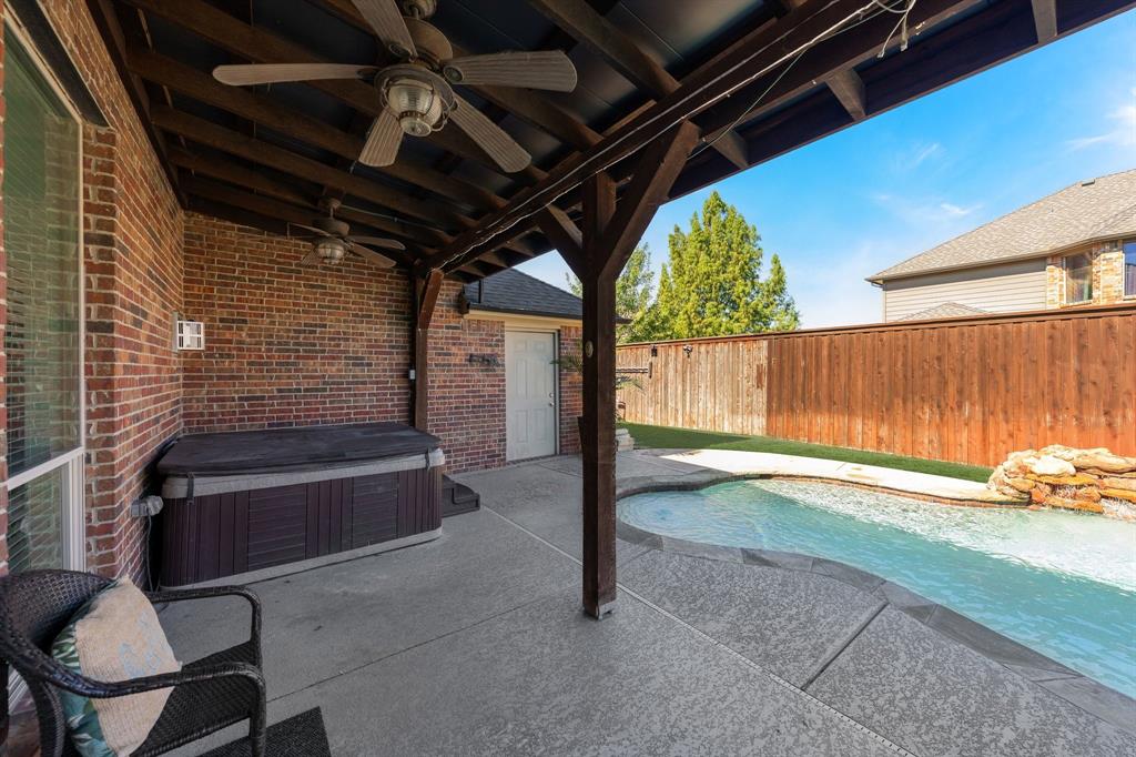 Covered patio featuring a ceiling fan, hot tub stays with the home, and concrete flooring