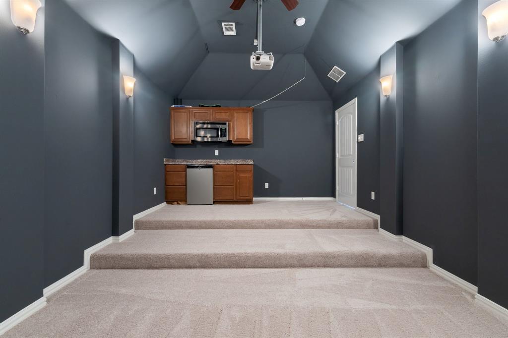 Tiered carpeting, recessed ceiling, built-in cabinetry, integrated microwave, and a beverage refrigerator