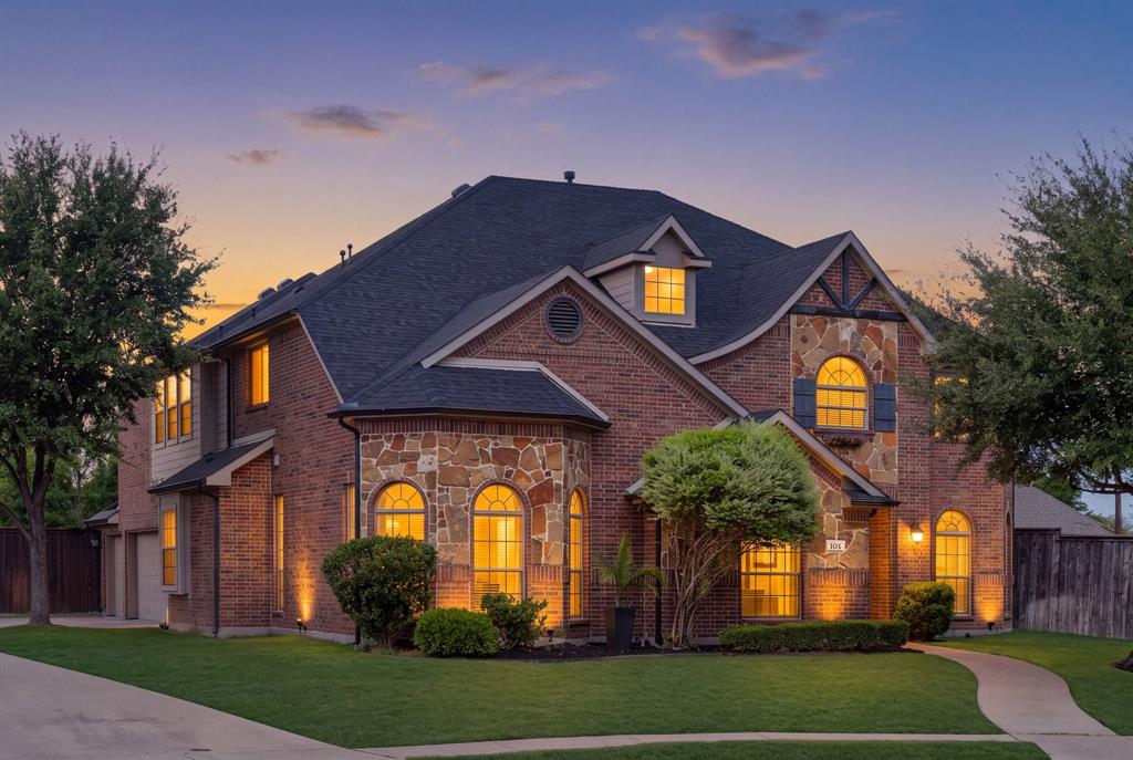 Brick and stone exterior with arched windows, gabled roofline, dormer windows, and established landscaping Brick and stone exterior with arched windows, gabled roofline, dormer windows, and established landscaping