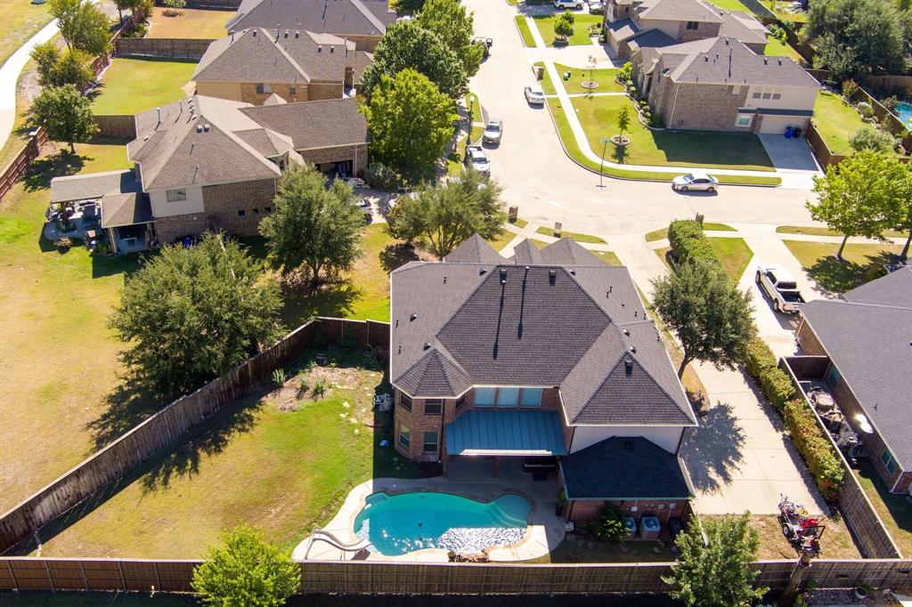 Expansive backyard featuring a large swimming pool, paved patio, and mature trees