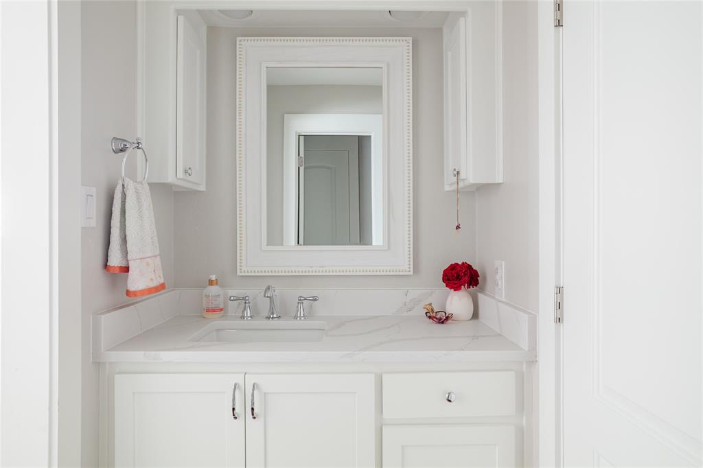 Spa-inspired custom bathroom vanity featuring a white cabinetry base with dual hardware pulls, a light-filled countertop with integrated sink, and polished chrome fixtures