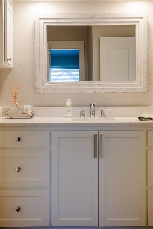 White shaker-style custom cabinetry with chrome hardware under a light-toned countertop