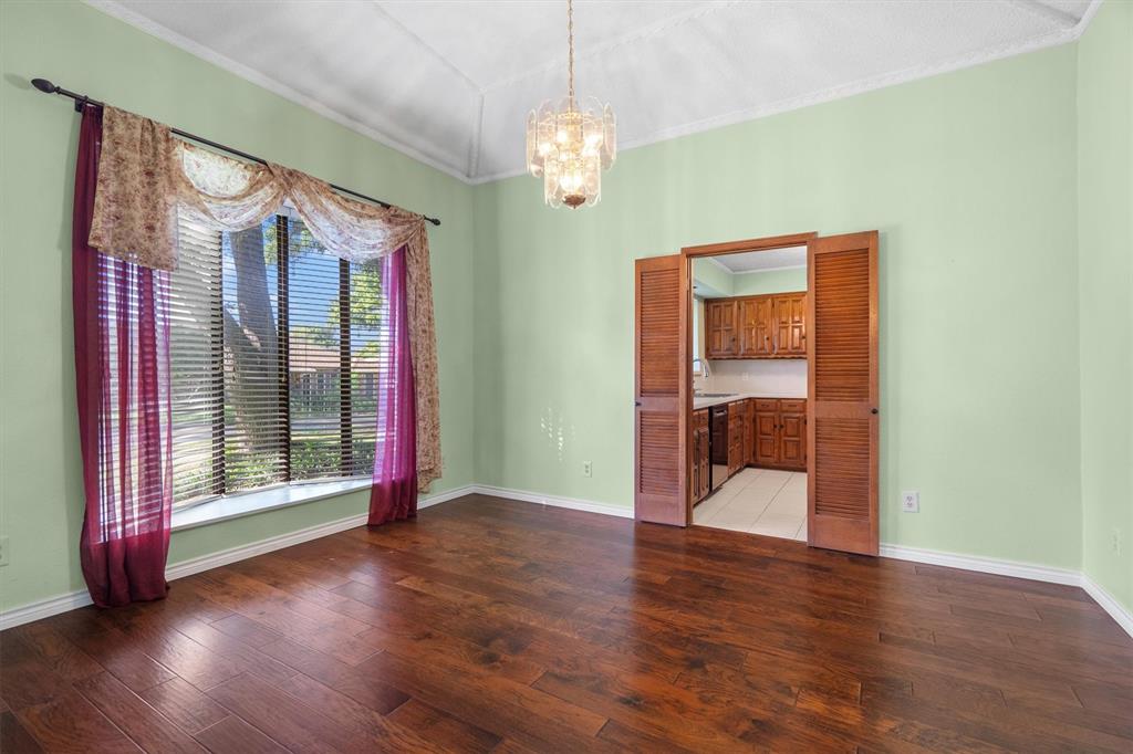 Spacious dining area adjacent to the kitchen, featuring hardwood floors and direct hall access