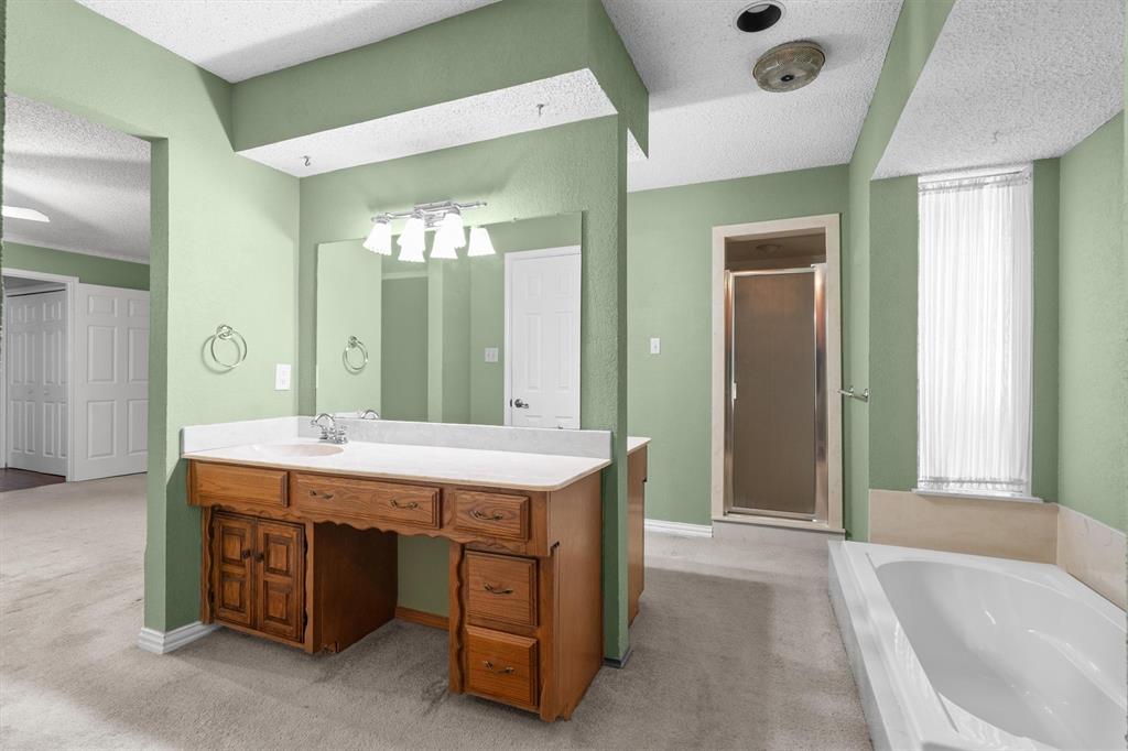 Primary bathroom has dual vanities, separate tub, and walk-in shower