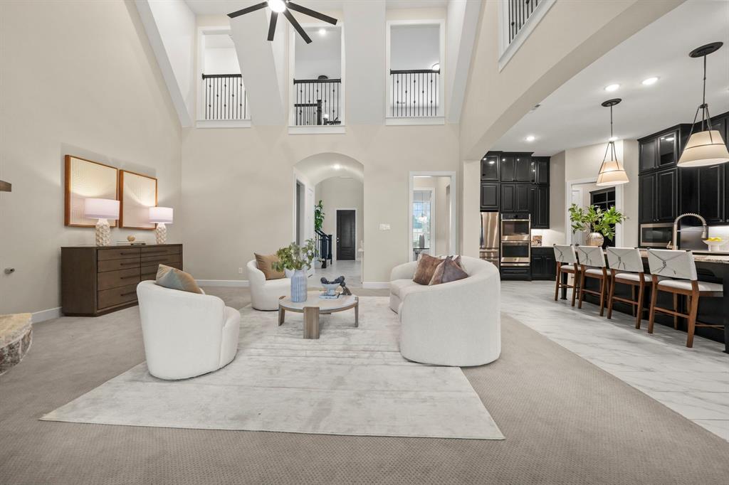 Vaulted ceilings with architectural balcony overlook, tile flooring, recessed lighting, and custom dark cabinetry with pendant light fixtures