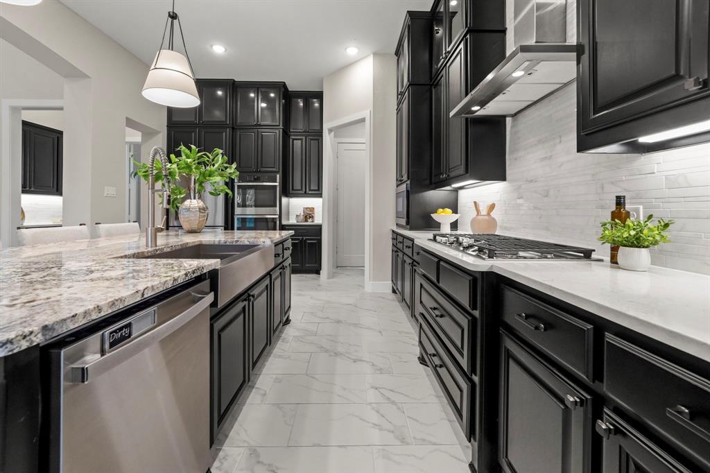 Kitchen featuring dark custom cabinetry, stone countertops, farmhouse-style sink, integrated gas cooktop, and tile flooring