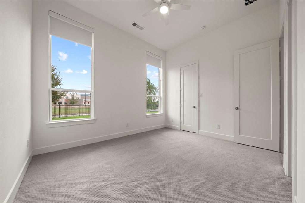 High ceilings, neutral carpeting, dual large windows, and a ceiling fan with integrated lighting