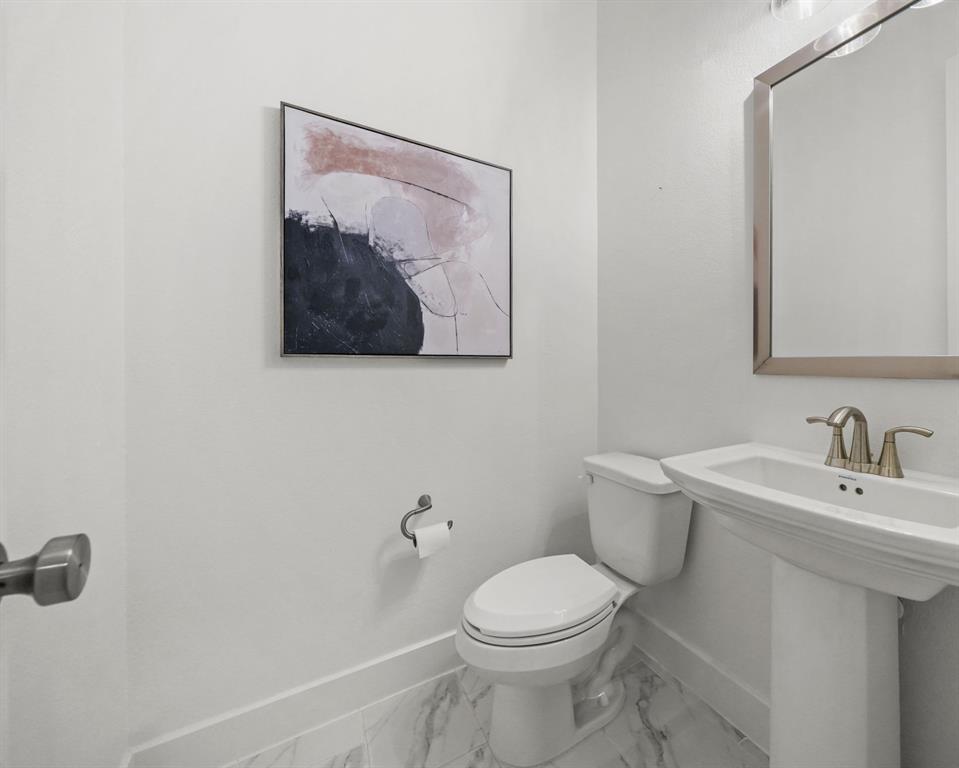 Powder room featuring a pedestal sink, metallic finish faucet, ceramic tile flooring, and wall-mounted hardware
