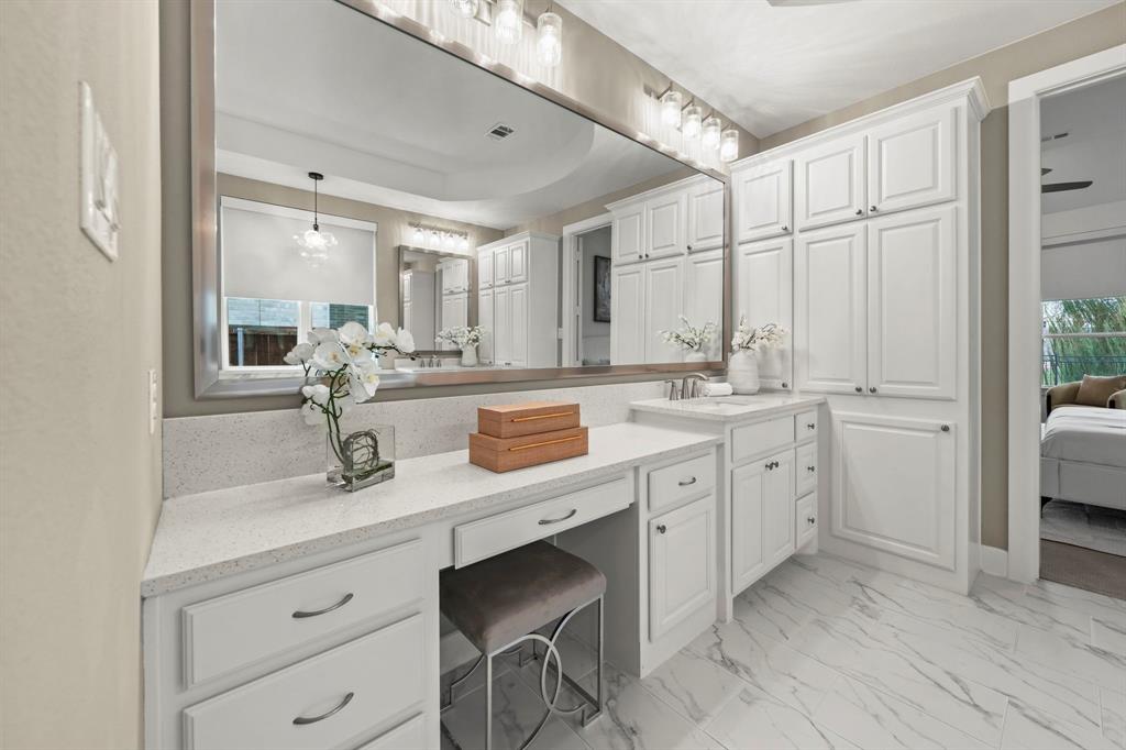 Vanity featuring a full-width mirror, white cabinetry, quartz countertop, and stone-finish tile flooring