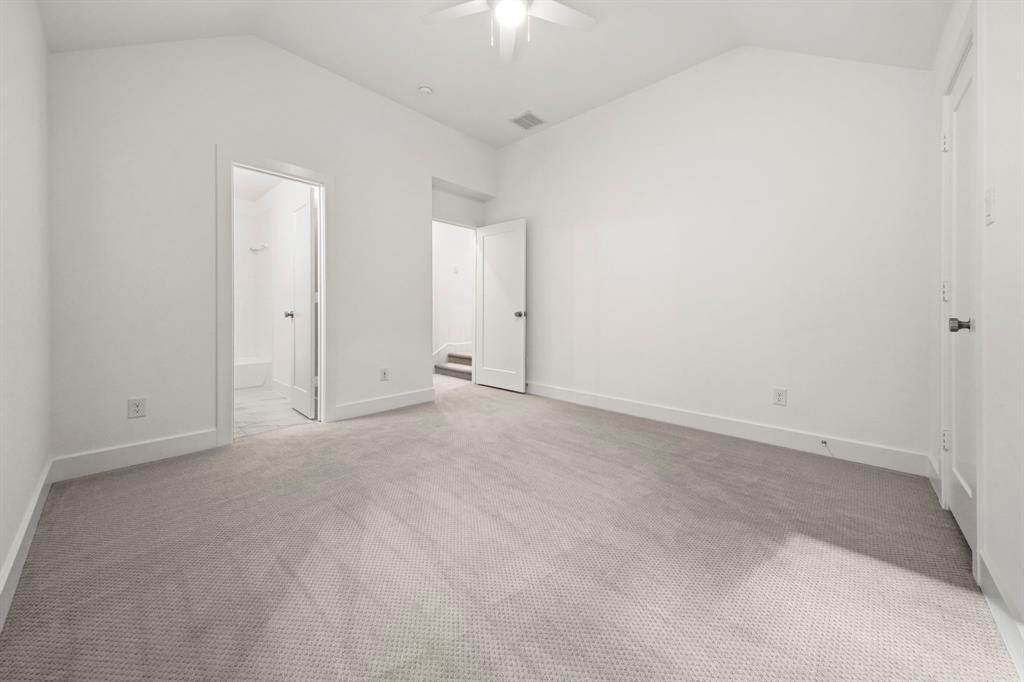 Vaulted ceiling featuring a central ceiling fan, neutral wall-to-wall carpeting, and solid-core interior doors
