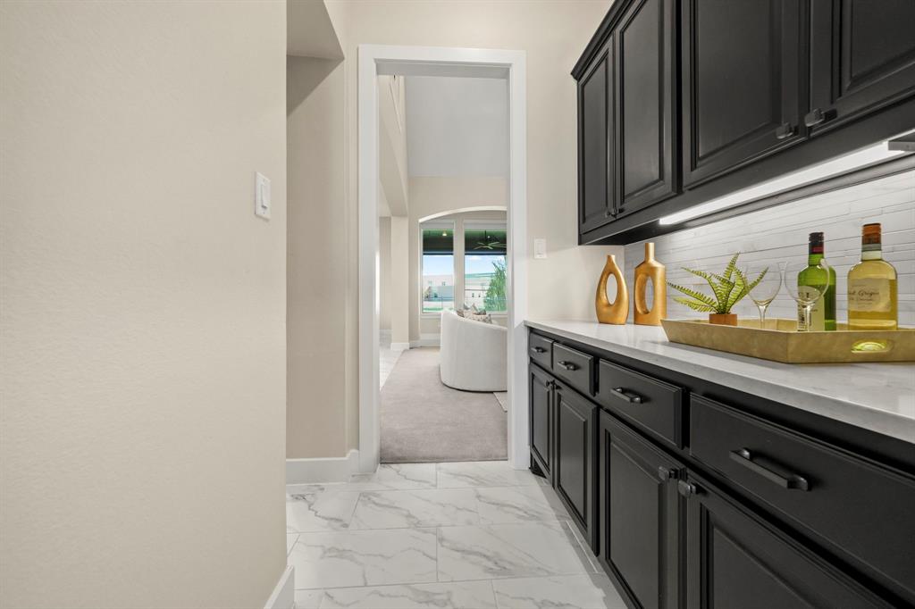 Built-in cabinetry with matte black finish, light-toned stone-look countertop, horizontal tile backsplash, and light-toned tile flooring