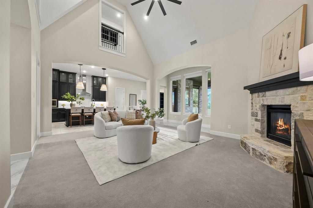 Vaulted ceilings, floor-to-ceiling stone fireplace, interior balcony, and arched window detailing